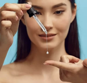 ragazza orientale che prova un trattamento anti-age versandosi una goccia di olio essenziale nelle mani